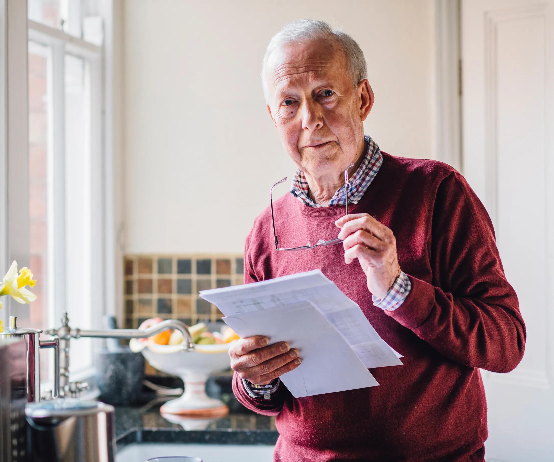 Elderly man looking at the camera holding his mail
