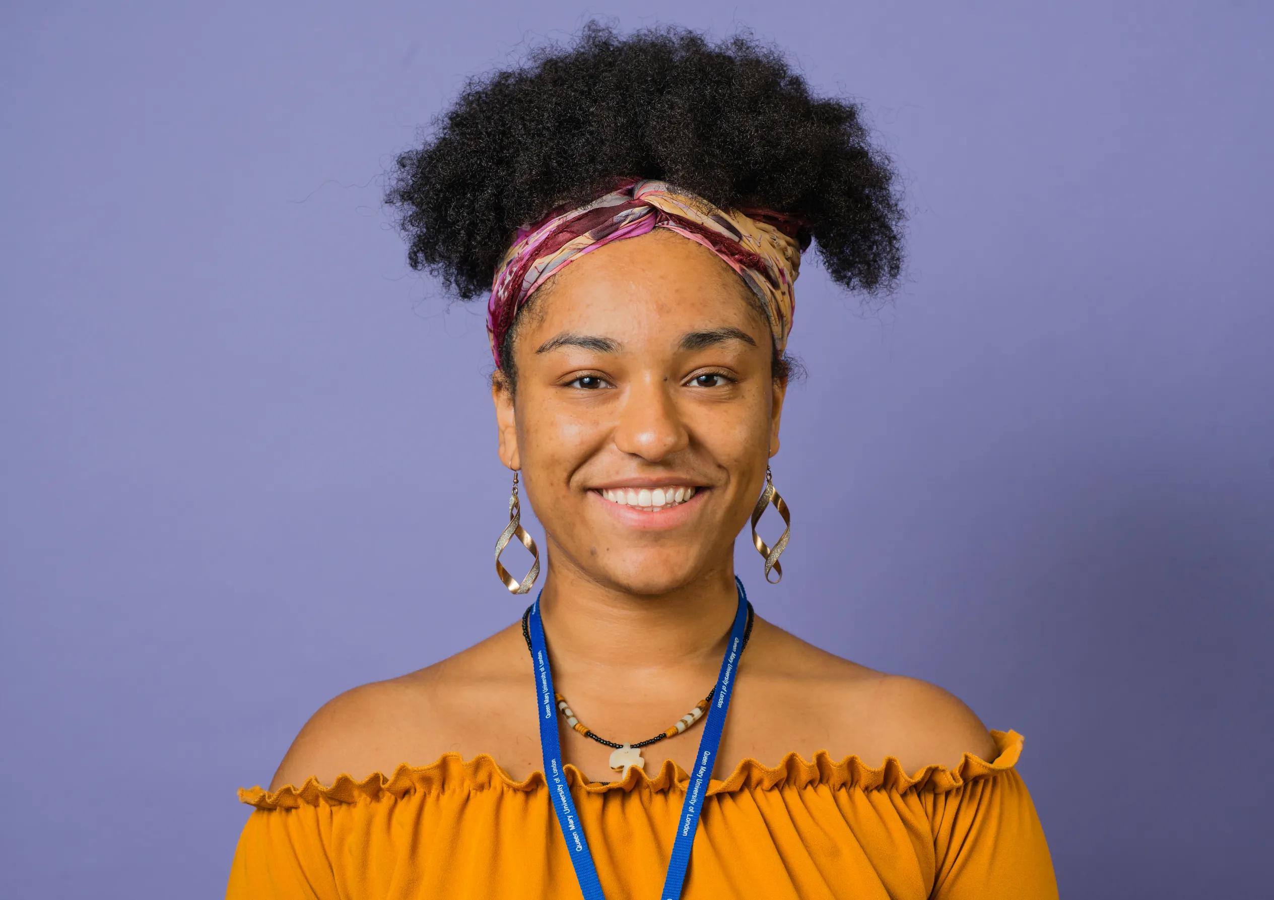 University student smiling with a purple background