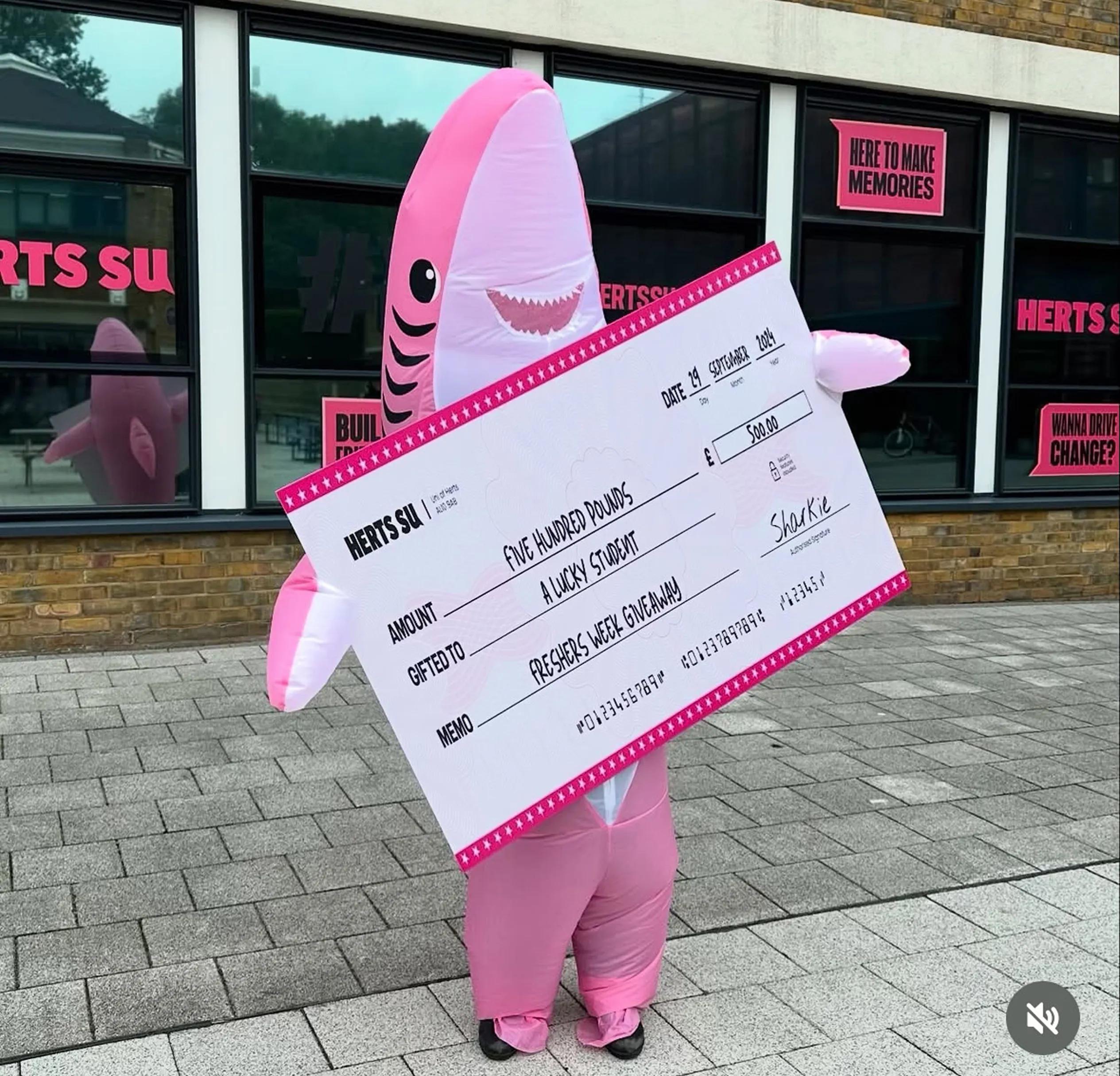 Mascot of a shark holding a giant cheque