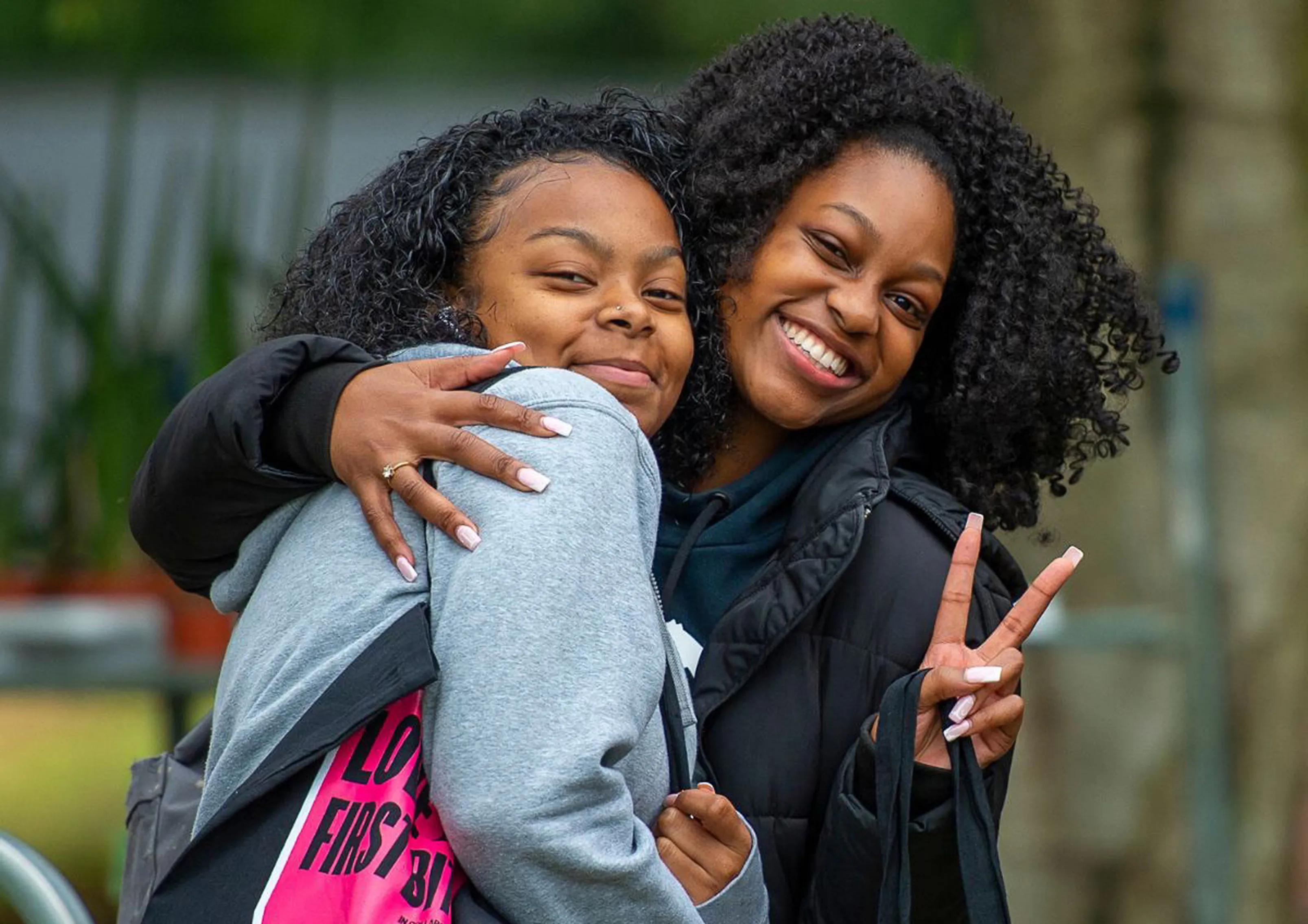 Two girls hugging while one wears a Herts SU tote bag