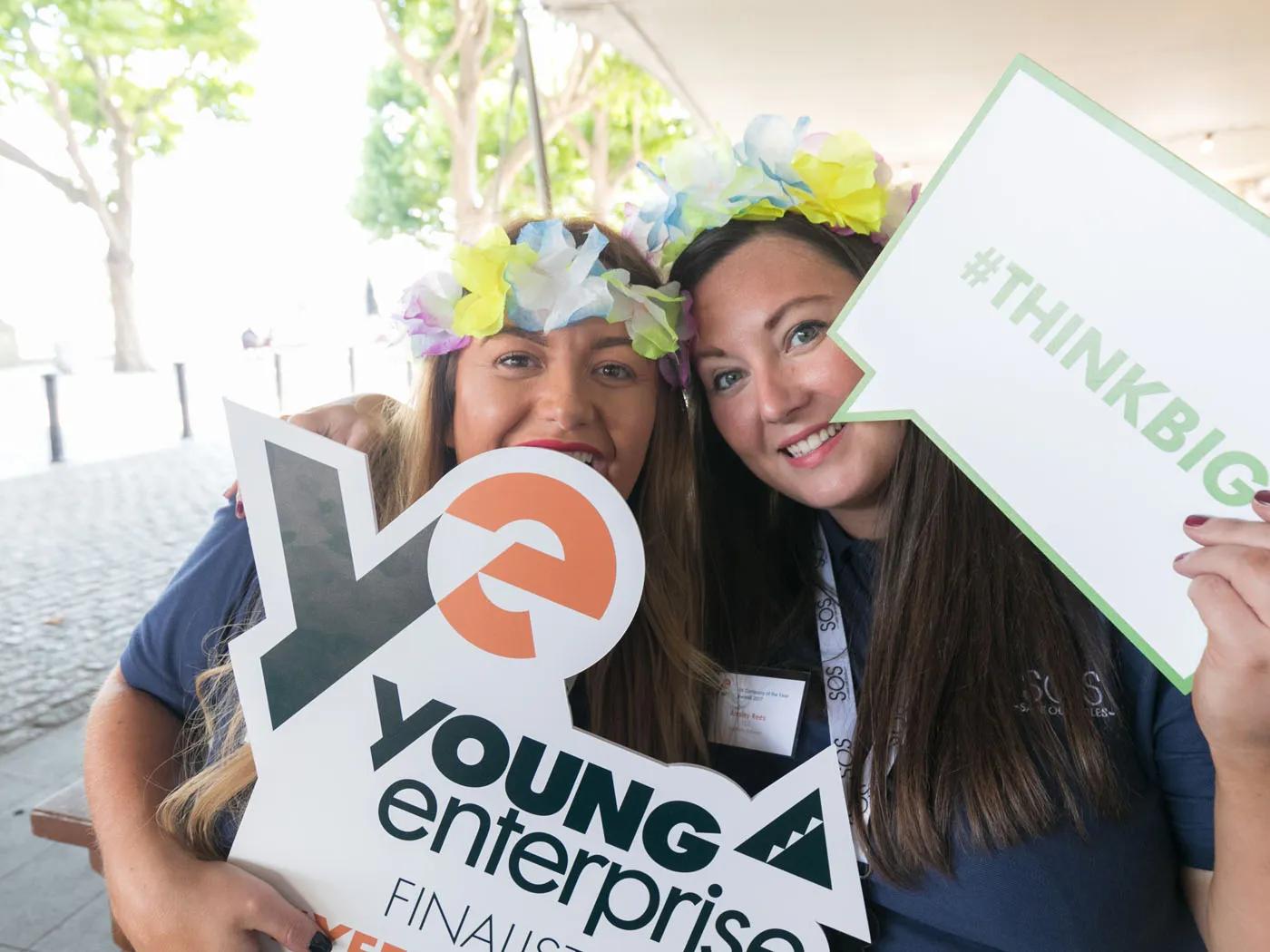 two people holding up a young enterprise sign